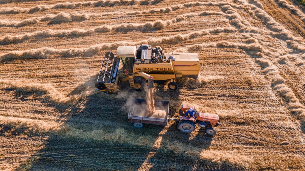 Agric technology of combine harvester unloads harvested grain into a tractor trailer in a dry field.