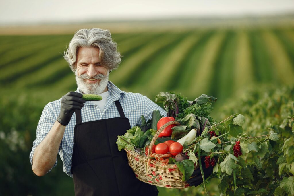 A farmer holding a basket of fresh vegetables while standing in a green agricultural field, displayed under an “Attachment Details” heading.
