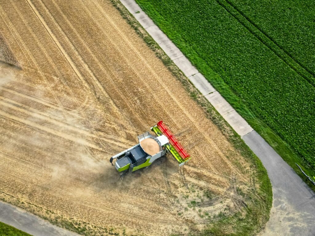 smart farming Aerial view of a tractor harvesting crops on a golden agricultural field near green farmland.