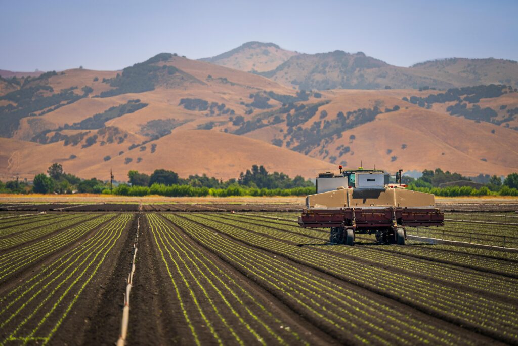 a farming image of a tractor working on cultivated soil.
