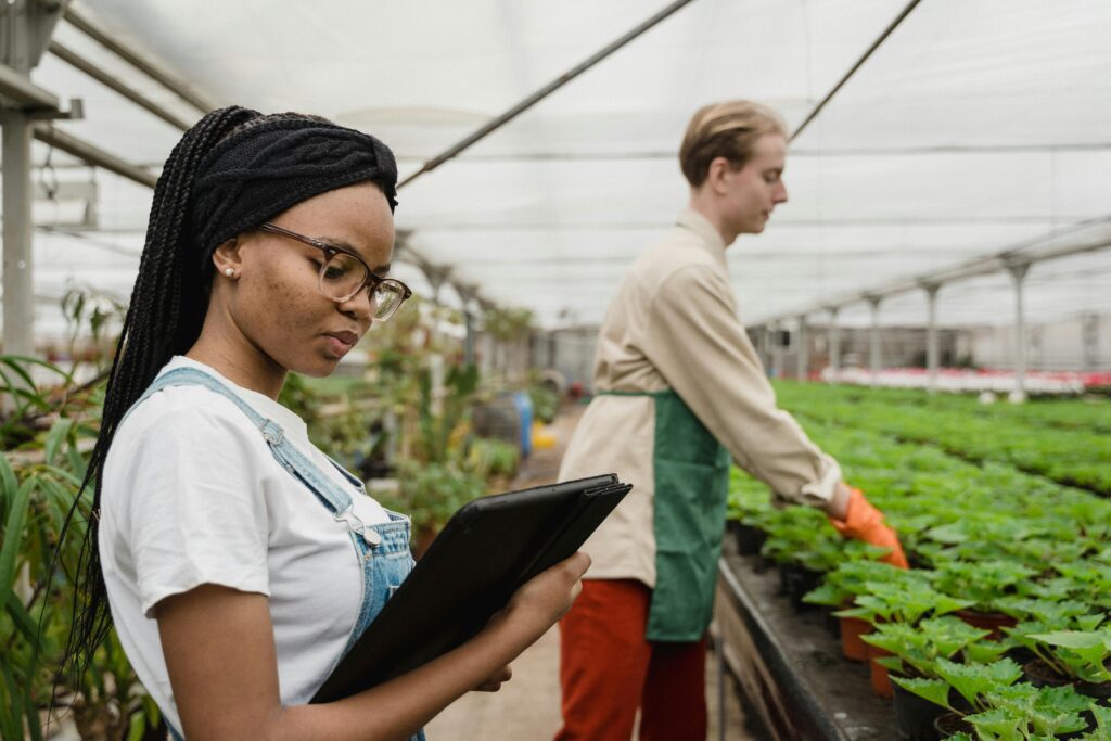
A media library screen showing a selected image of two people working with a tablet in a greenhouse environment.